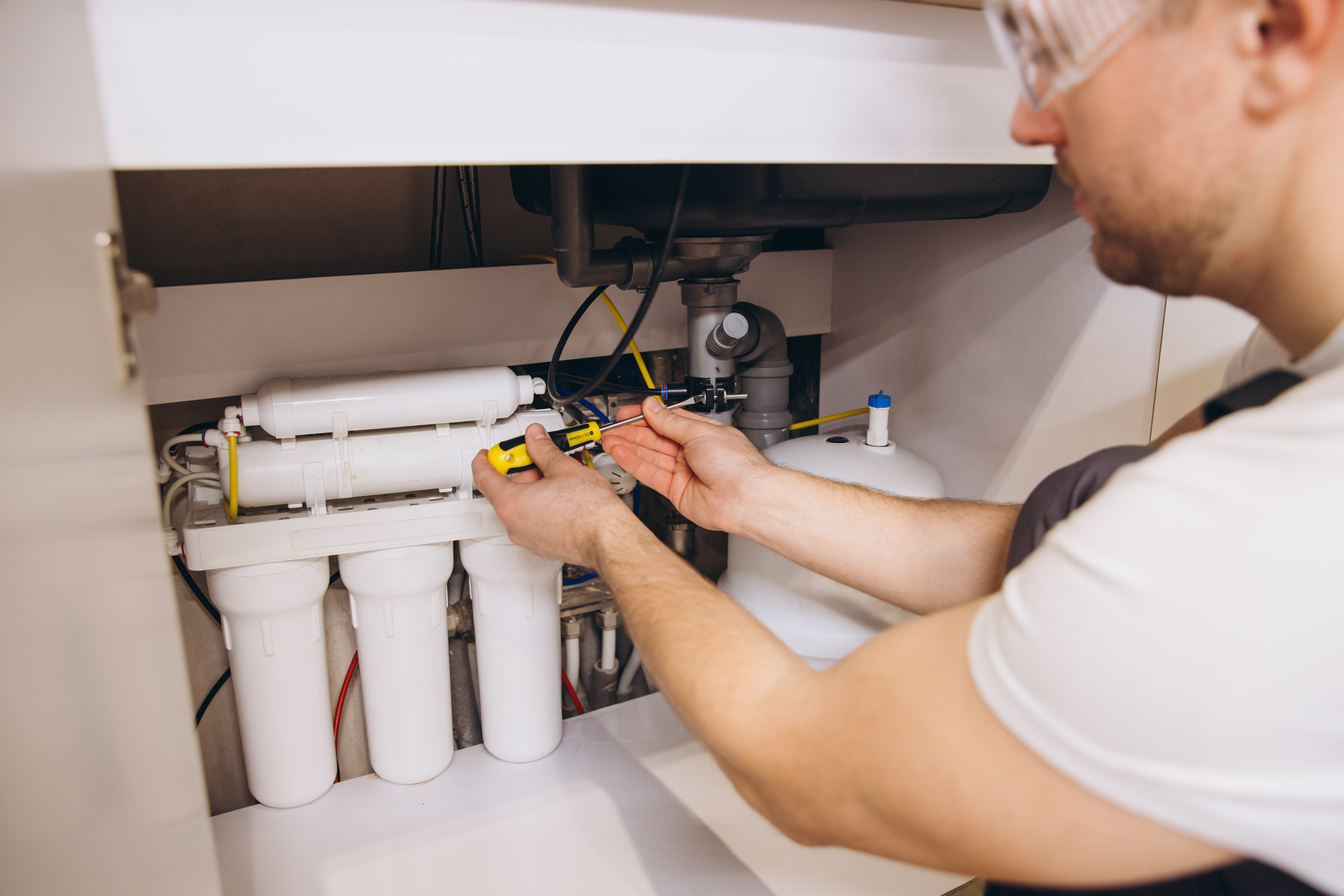 Technician installing water filtration system under sink